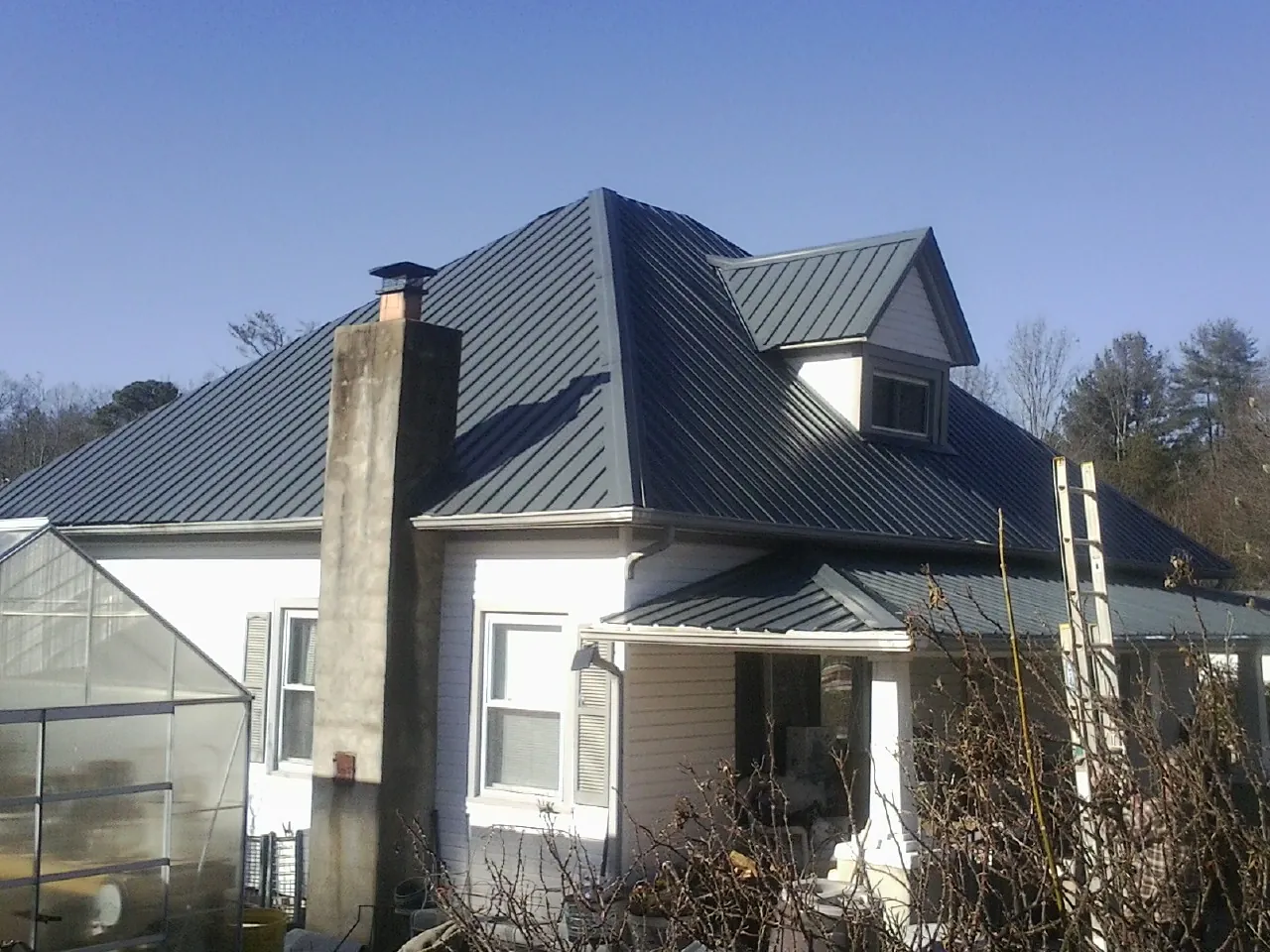Dark blue standing seam metal roof on a white farmhouse with dormer — Slate & Tile Roof Repair by Roofing Brothers in McCall