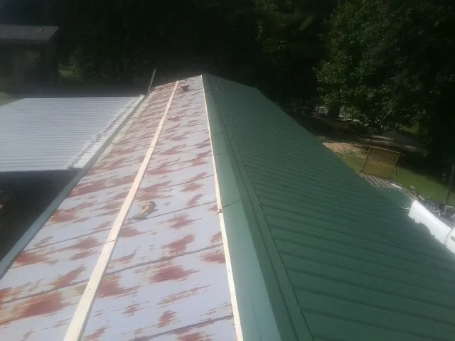 Old rusted panels beside newly installed green metal roofing — Wind Damage Roof Repair by Roofing Brothers in McCall