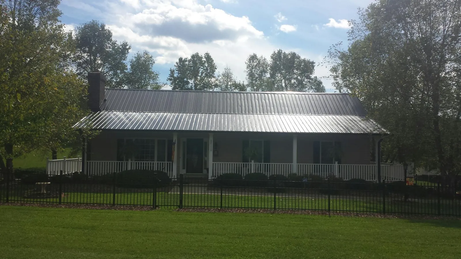 Gray metal roof on a brick ranch with a full width front porch — Gutter Guard Installation work by our crew in McCall